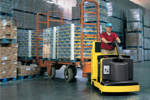 worker driving tow tractor through warehouse